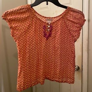 Shirt with short sleves has red ish pink flower print on